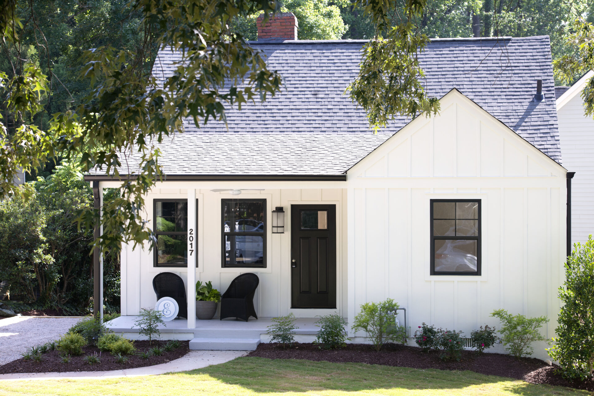 A white house with black shutters and a porch.